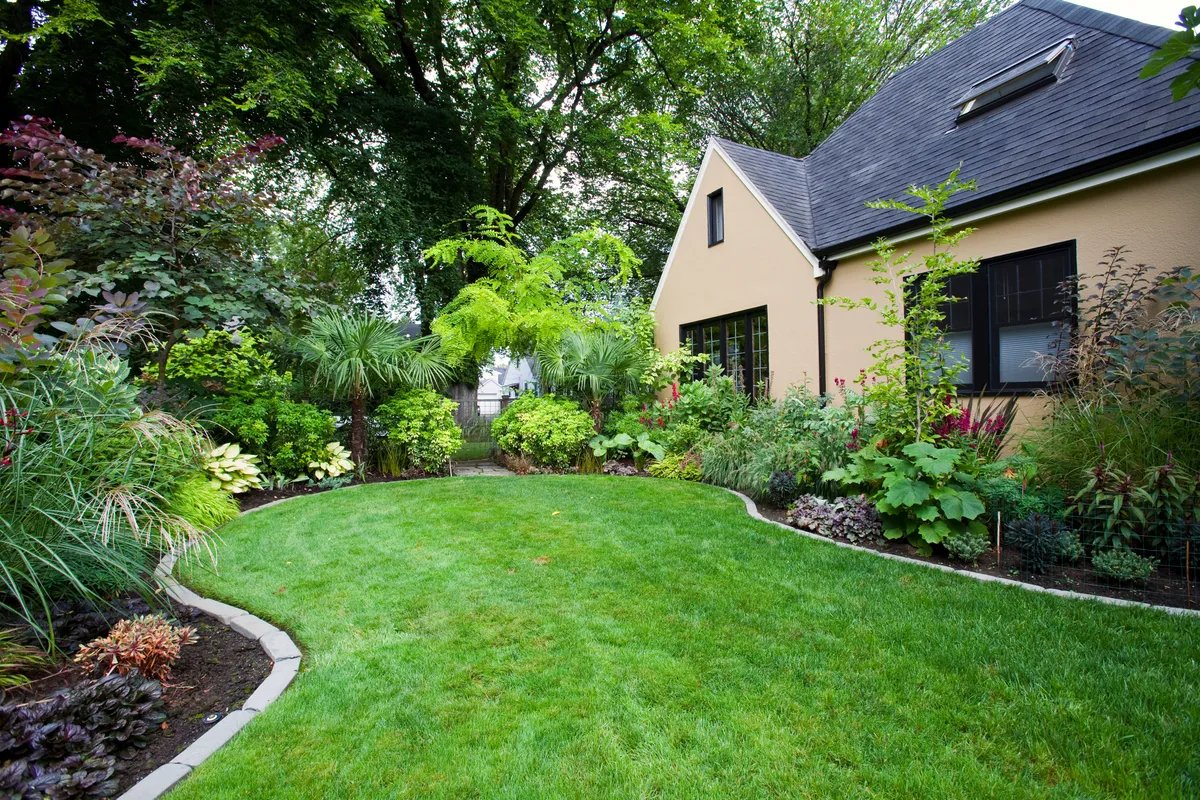 A lush, professionally landscaped backyard with layered plantings beside a home